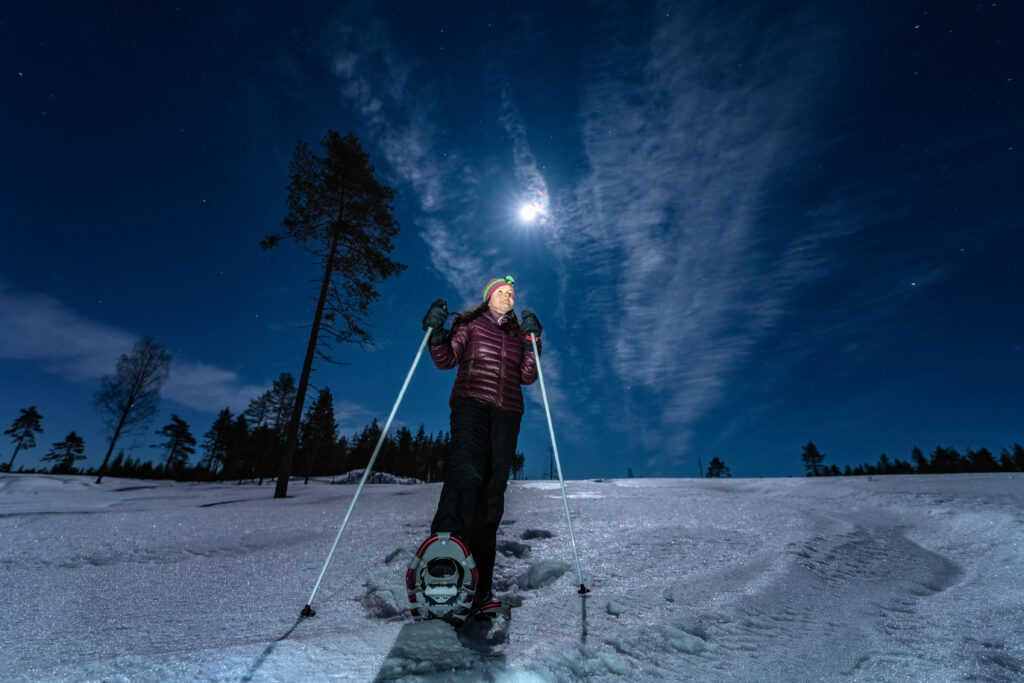 woman snowshoeing under a full moon