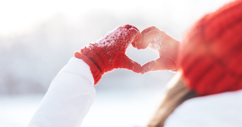 women in the snow making a heart with her hands
